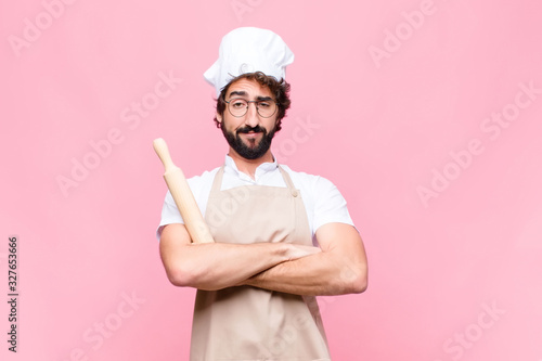 Fotografía young crazy baker man with a cook tool against pink wall