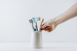 Hand takes eco friendly toothbrush from a white cup. White background with space for text. Dental care concept