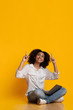 © Prostock-studio - Excited black woman sitting with laptop on floor and pointing upwards