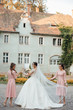 Beautiful bride and her friends- bridesmaids having fun and walking near the building after wedding ceremony
