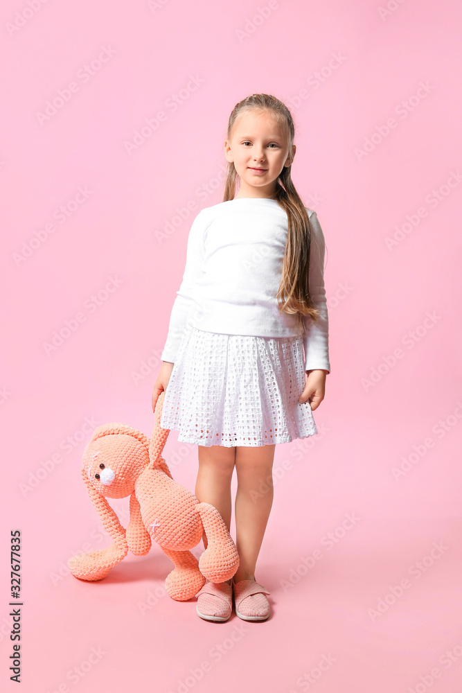 Cute little girl with toy on color background