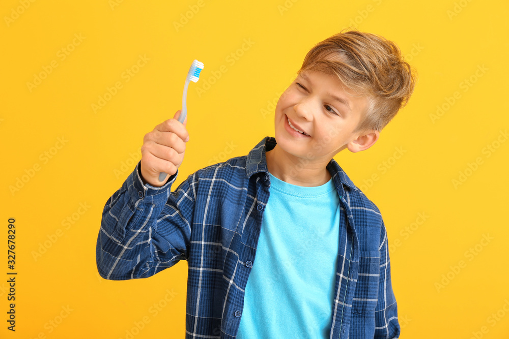 Cute little boy with toothbrush on color background