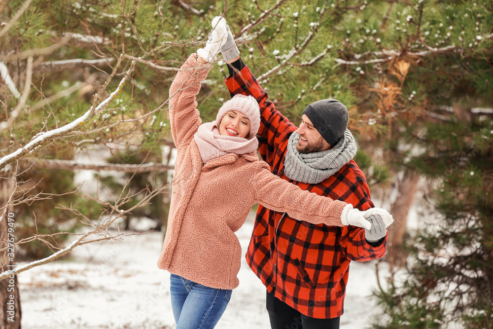 Happy young couple dancing in park on winter day