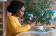 Concentrated black girl using smartphone at cafe