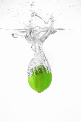 Falling of fresh lime into water against white background