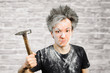 Dirty young builder guy freak in plaster is hold a hammer on brick wall background at home during repairs