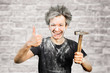 Dirty young builder guy in plaster is hold a hammer on brick wall background at home during repairs