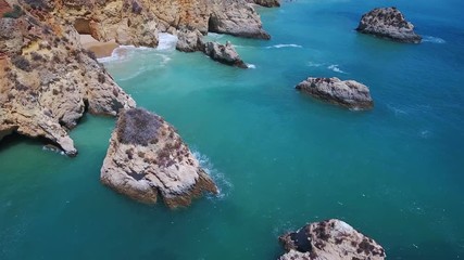 Wall Mural - Aerial view from above, waves splashing on reefs on the Portuguese Algarve coast.