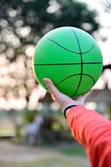 Woman wearing an orange shirt holding a green  ball on a bokeh background.The viewpoint of exercise is good for health.