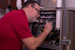 HVAC Tech Making A Repair To Furnace  Red Shirt 