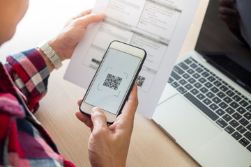 The butler is using a mobile phone to scan the QR code for the bill through the app. Convenient, fast, is an option of modern.