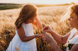 © Strelciuc - Beautiful caucasian girl and her mother posing against the sunshine on a wheat field holding some seeds