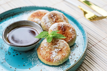 Wall Mural - Vegan tofu cheese pancakes on blue plate with honey closeup