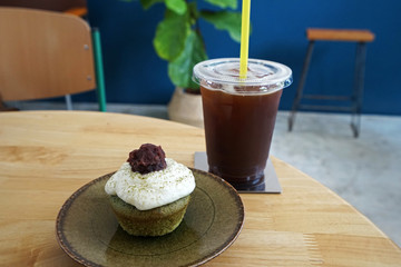 Matcha green tea cupcake served with Iced black Americano coffee on wooden table