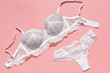 Sexy white lace bra and panties on pink background. Stylish lingerie flat lay. Underwear fashion concept.