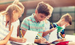 © Syda Productions - primary education, friendship, childhood, communication and people concept - group of happy elementary school students with notebooks sitting on bench outdoors