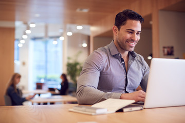 Businessman At Desk In Modern Office Work Space With Laptop