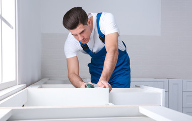 Poster - Maintenance worker installing new kitchen furniture indoors