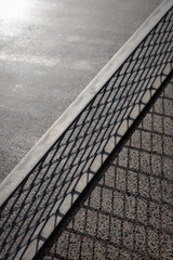 Street table tennis or ping pong net and stone table. Monochrome grey background.Different shades of gray.Outside summer activity, sports game unusual conceptual shot. Diagonal, macro shot, copy space