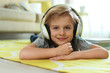 © New Africa - Cute little boy with headphones listening to audiobook at home