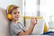 © New Africa - Cute little boy with headphones and smartphone listening to audiobook at home