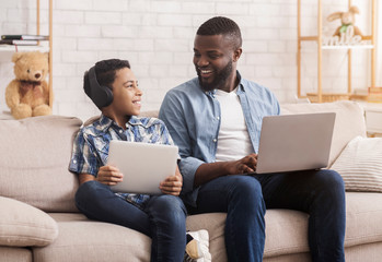 Canvas Print - Black Father And Son Using Digital Tablet And Laptop At Home