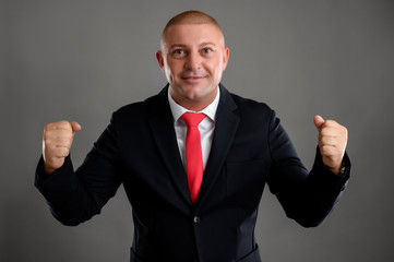 Businessman dressed in black suit enjoys raised arms