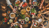 Fototapeta Na ścianę - Turkish breakfast. Flat-lay of family eating pastry, vegetables, greens, cheeses, fried eggs, jams from oriental tableware, tea in copper pot and tulip glasses over rustic wooden background, top view