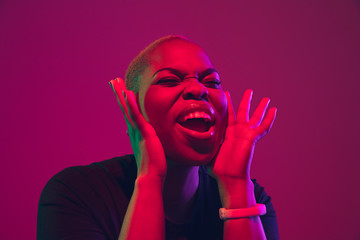 Wall Mural - Shouting, calling. African-american young woman's portrait on purple background. Beautiful model in black shirt. Concept of emotions, facial expression, sales, ad, inclusion, diversity. Copyspace.