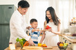 © Kawee - Lovely cute Asian family making food in kitchen at home. Portrait of smiling mother, father and child standing at cooking counter. Kid playing with dad and mom smile. Happy family activity together.