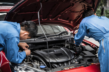 Two auto mechanic doing car service and maintenance.