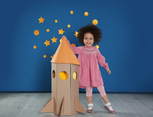 Cute African American Child Playing With Cardboard Rocket Near Blue Wall