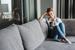 © Drobot Dean - Image of smiling nice woman using cellphone while sitting on sofa