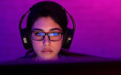 professional female gamer playing online videogame at home, low light