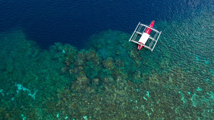 Wall Mural - Aerial top down view of boat moving in open sea with clear and turquoise water on over coral reef,  Boat left the tropical lagoon, Moalboal, Oslob, Cebu Island, Philippines.