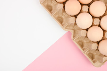 A tray of eggs on a white and pink background. eco tray with testicles. minimalistic trend, top view. Egg tray. Easter concept.