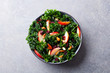 Kale salad with apples, cranberry and nuts. Grey background. Top view.