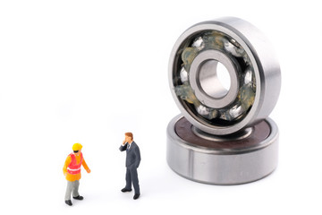 Miniature People : Business man talk with engineer and standing in front of ball bearing which have Lithium grease (NLGI 3) isolated on white background. Industrial and business concept.