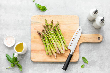 Wall Mural - Asparagus cooking concept, top down view on a cutting board with fresh bunch of asparagus, lying down on a kitchen table