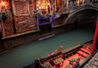 moored gondola on narrow canal with bridge and christmas lights 
