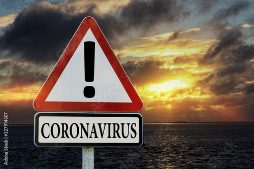 Cuadros en Lienzo Coronavirus - Verkehrsschild vor Sonnenaufgang am Meer