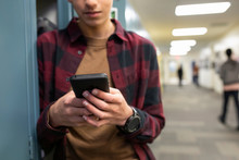Junior High Boy Student Texting With Smart Phone At Lockers In Corrido