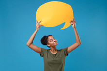 Pretty Young African American Woman Girl In Casual T-shirt Posing Isolated On Bright Blue Background. People Lifestyle Concept. Mock Up Copy Space. Hold Yellow Empty Blank Say Cloud, Speech Bubble.