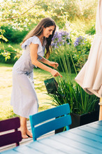 Pretty Young Woman Watering Plants In Summer Garden