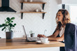 © undrey - Young woman sitting in front open laptop and working at home