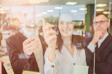 Wall Mural - Three businesspeople discussing and planning concept. Front of glass wall marker and stickers. Startup office