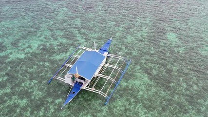 Wall Mural - Aerial top down view of boat moving in open sea with clear and turquoise water on over coral reef,  Boat left the tropical lagoon, Moalboal, Oslob, Cebu Island, Philippines, 4K.