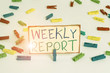 Writing note showing Weekly Report. Business concept for information on what have become known within the week Colored clothespin papers empty reminder white floor background office