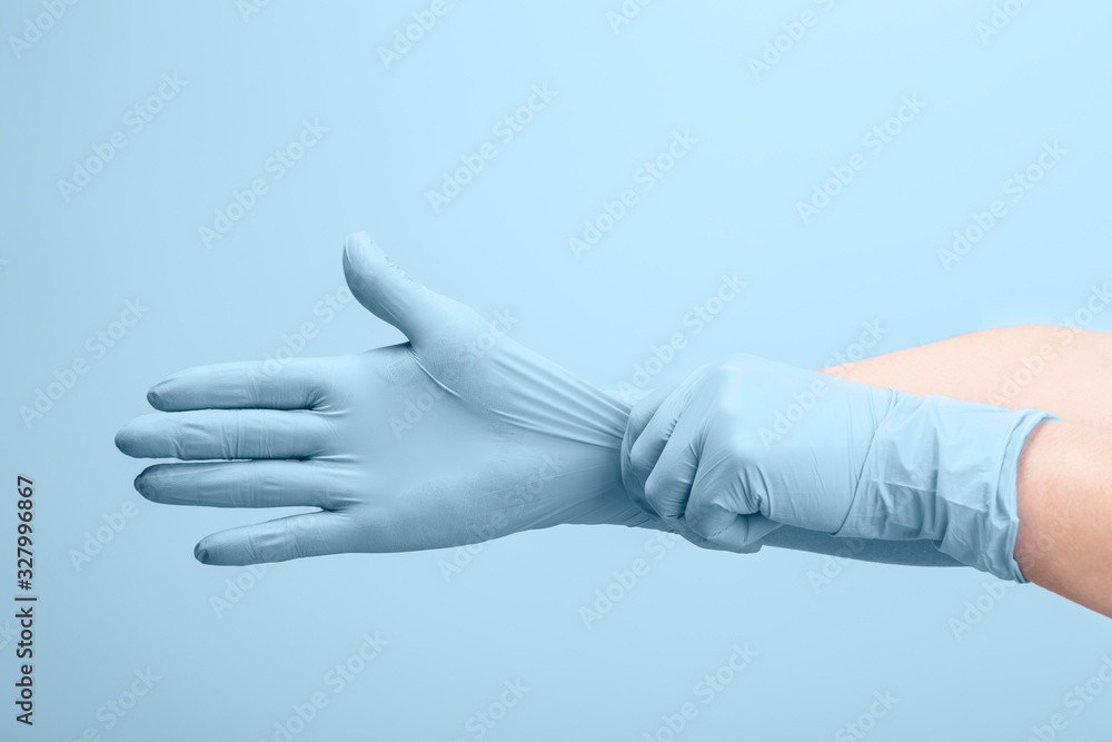 Female doctor's hands putting on blue sterilized surgical gloves - obrazy, fototapety, plakaty 