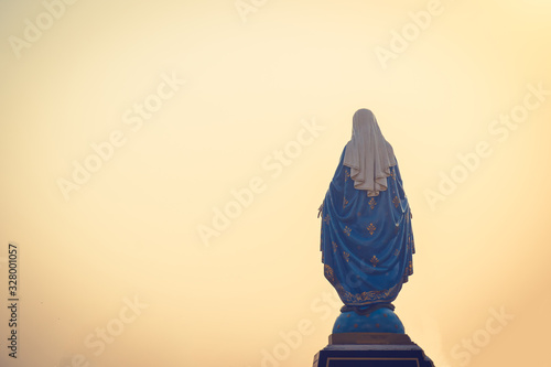 Fotografía Silhouettes of the blessed Virgin Mary statue figure in a warm tone - sunset scene